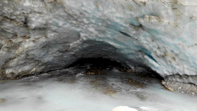 Aerial flyover from the ice cave of the Zinal glacier in Valais, Switzerland with a view of the melting glacial water stream, crevasse and alpine valley