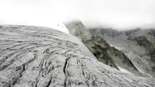Panning aerial view towards the crevasses at the edge of the Moiry glacier near Grimentz in Valais, Switzerland with the glacial tongue and lake in the valley in view