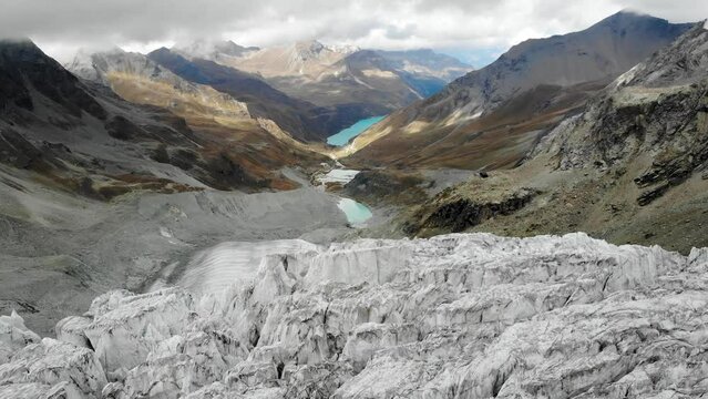 Aerial view over the edge of the Moiry glacier near Grimentz in Valais, Switzerland with of the glacial tongue and lake in the valley in the background of the crevasses