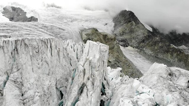 Aerial flyover through the ice crevasses of the Moiry glacier near Grimentz in Valais, Switzerland with on a cloudy summer afternoon