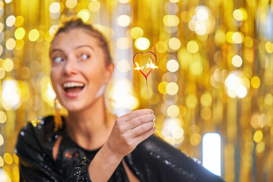 Young woman holding love sparkle over gold background