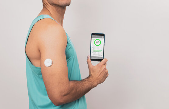 Unrecognizable young man shows his mobile with glucose monitor continuous blood sugar test app, glucose measurement, White background.