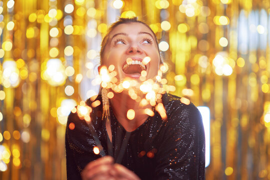 Young woman holding sparkle over gold background