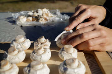a woman's hand cutting mushrooms with a knife on a camping table in winter