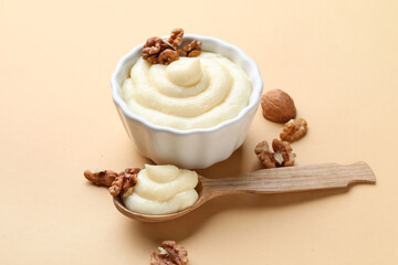 Ramekin of tasty vanilla pudding with walnuts on color background