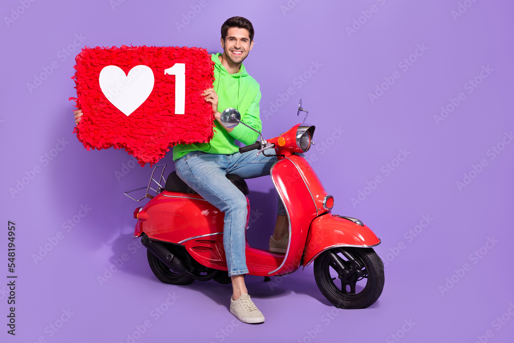 Sticker Full length photo of optimistic attractive guy wear green hoodie sit on motorcycle hold big red like isolated on purple color background