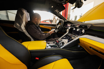 Mechanic using digital tablet, while sitting in yellow sport car suv.