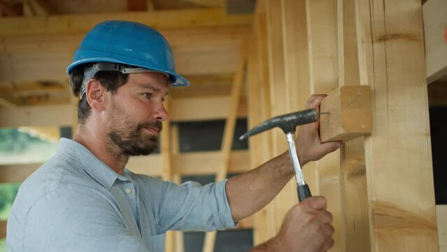 Carpenter Working On Building Site Of Sustainable Wooden House.