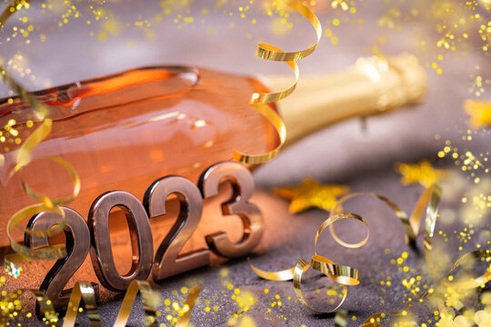 Happy new year 2023 background. New year card with bottle of сhampagne, festive decorations, lights, gift. 2023 New Year festive background