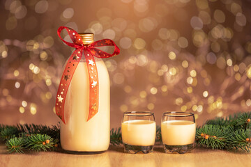 bottle of homemade eggnog with two glasses on spotted background