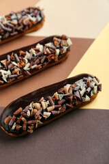 Delicious chocolate eclairs on color background, closeup - obrazy, fototapety, plakaty