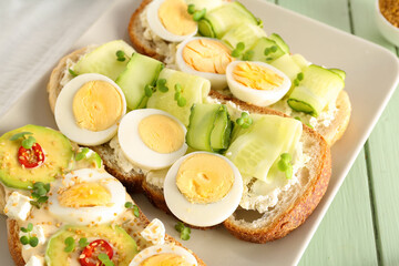 Plate of tasty toasts with boiled egg on color wooden table, closeup