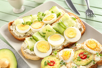 Plate of tasty toasts with boiled egg on color wooden table, closeup