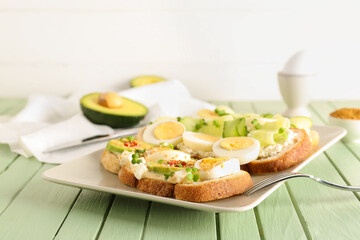 Plate of tasty toasts with boiled egg on color wooden table, closeup