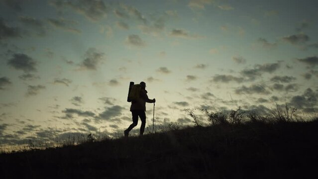 Man walking up a hill at sunrise.