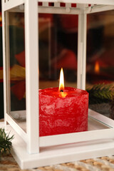 Christmas lantern with burning candle on rug, closeup