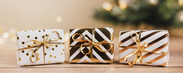 White gift boxes tied golden ribbons and bow on wooden background. Online christmas shopping and sale. Merry Christmas and Happy New Year holiday greeting card. Copy space. Banner
