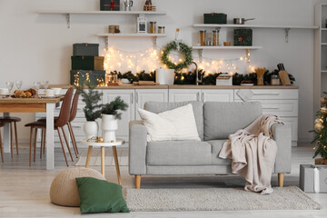 Interior of kitchen with Christmas wreath, dining table and sofa
