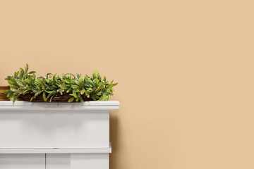 Christmas mistletoe wreath on fireplace near beige wall