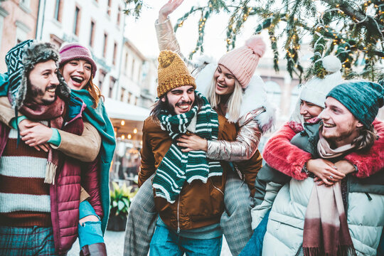 Happy group of friends wearing winter clothes having fun celebrating Christmas day together - Cheerful young people laughing together walking on city street - Winter holidays and friendship concept