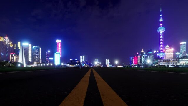 An animation of multiple vehicles traveling on the main road into a modern cosmopolitan city at night.
