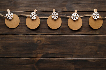 Christmas decorations: clothespins with snowflake decoration and writable labels, on a wooden background. Top view.