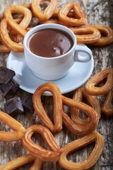 Churros con chocolate sobre una mesa rústica de madera, dulce tradicional.