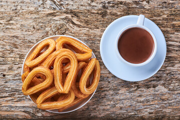 Churros con chocolate sobre una mesa rústica de madera, dulce tradicional.