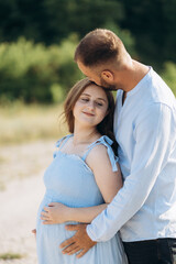 Portrait of a lovely couple standing together on the greenfield. Happy couple expecting a baby, young family concept