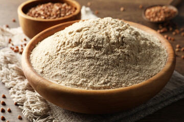 Fototapeta na wymiar Bowl of buckwheat flour and cloth on wooden table