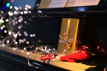 Christmas gift, decor and glowing lights on black piano, closeup