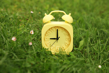 Yellow alarm clock on green grass outdoors