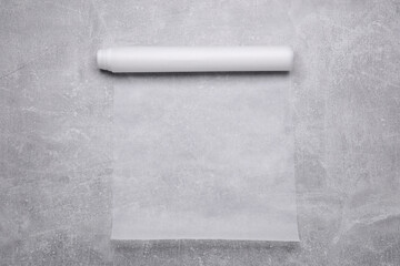 Roll of baking paper on light grey table, top view