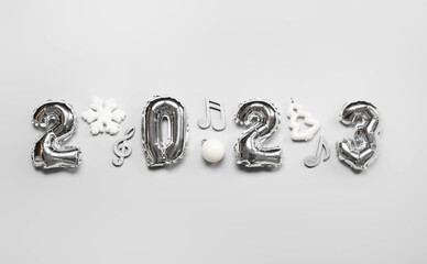 Figure 2023 made of balloons with Christmas decor and note signs on grey background