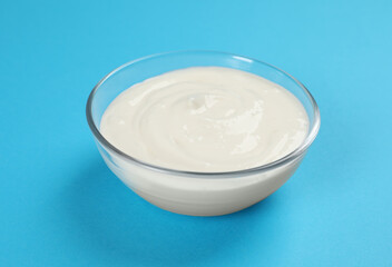 Bowl of tasty organic yogurt on light blue background
