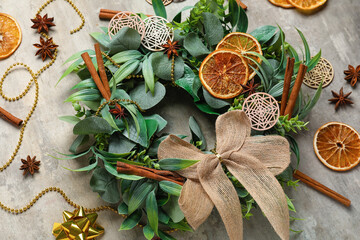 Stylish Christmas wreath with decorations, orange slices and cinnamon on grunge background, closeup