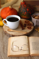 Cup of tea or coffee, seasonal spices, bowl of cookies, blanket, pumpkins, colorful leaves, books and tangerines on wooden table. Cozy hygge at home. Selective focus.