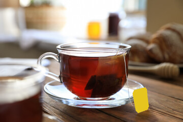 Tea bag in glass cup on wooden table indoors, closeup