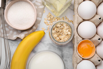 Different ingredients for cooking tasty oatmeal pancakes on white marble table, flat lay
