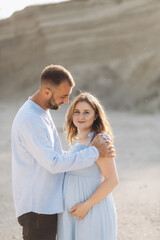 Obraz premium Portrait of a lovely couple standing together on the greenfield. Happy couple expecting a baby, young family concept