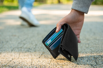 Man picking lost wallet from ground outdoors, closeup. Space for text - obrazy, fototapety, plakaty