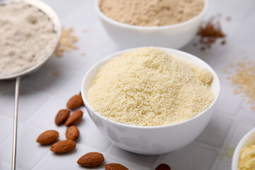Bowls with different types of flour on tiled table, closeup