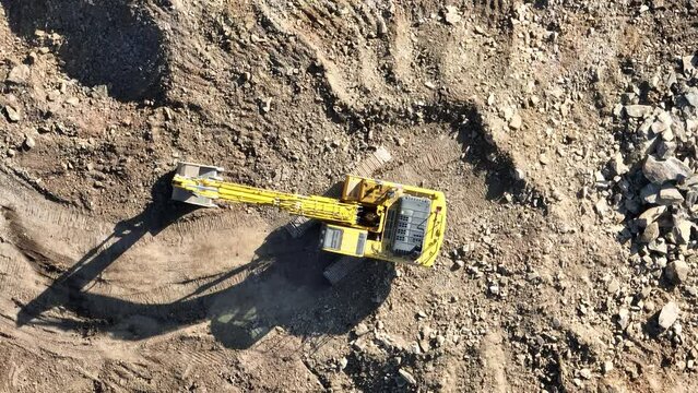 Industrial mine excavators are digging the soil in the construction site and loading trucks. Aerial drone top view. 