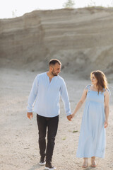 Portrait of a lovely couple standing together on the greenfield. Happy couple expecting a baby, young family concept