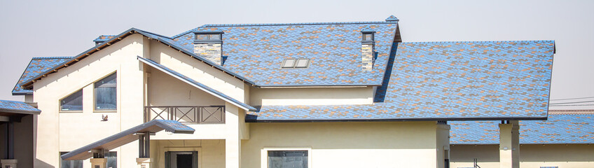 Roofs of houses from a metal profile against the sky. Roofing. Metal tiles on the roofs of houses.