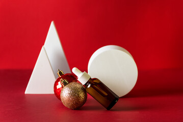 Christmas Minimalistic Composition with Brown Glass Serum Bottle on Red Background with Golden and Red balls Health and beauty concept.