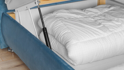 Storage drawer under bed with white blanket indoors, closeup