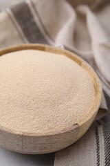 Granulated yeast in wooden bowl on table, closeup