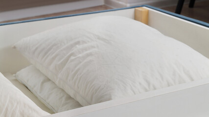 Fototapeta na wymiar Storage drawer under bed with white pillows indoors, closeup
