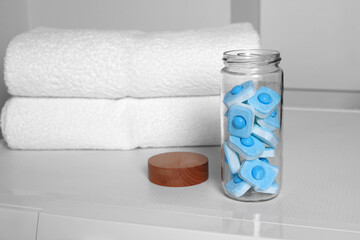 Glass jar with water softener tablets on washing machine in bathroom, space for text